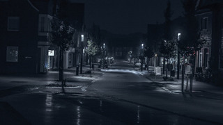 Ночная улица в небольшом городе, освещённая фонарями рядом с домами